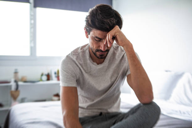 Un homme seul se tient la tête, il semble abattu, réfléchissant à une issue à sa situation.