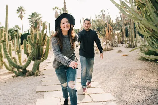 Couple souriant marchant ensemble sur un chemin, illustrant le cheminement vers une relation de couple plus harmonieuse.